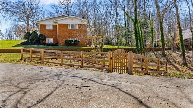 view of property exterior with a fenced front yard, brick siding, a lawn, and a gate