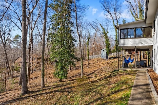 view of yard with an outbuilding, a shed, and a sunroom