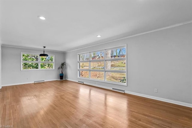 spare room featuring visible vents, baseboards, wood finished floors, and ornamental molding