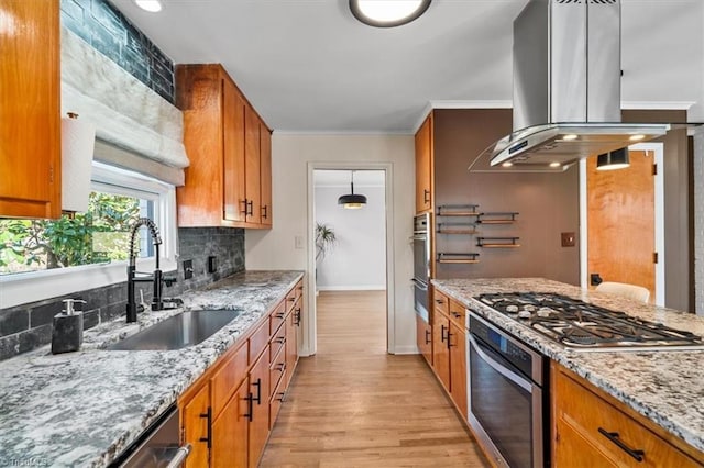 kitchen featuring island exhaust hood, a sink, decorative backsplash, stainless steel appliances, and crown molding