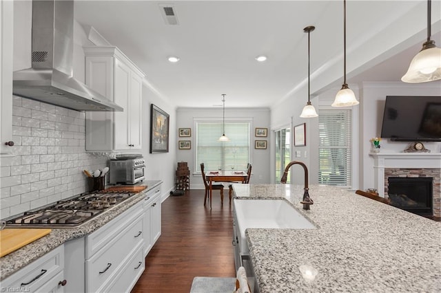 254 Kilbourne Dr, Advance, NC 27006 - kitchen with wall chimney exhaust hood, stainless steel gas cooktop, dark wood-type flooring, white cabinetry, and light stone countertops