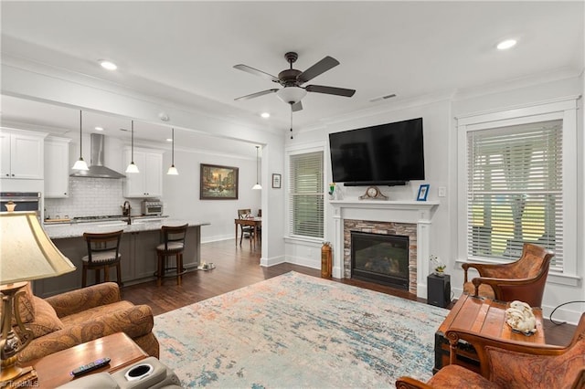 254 Kilbourne Dr, Advance, NC 27006 - living area featuring ceiling fan, dark wood-style flooring, a stone fireplace, ornamental molding, and recessed lighting