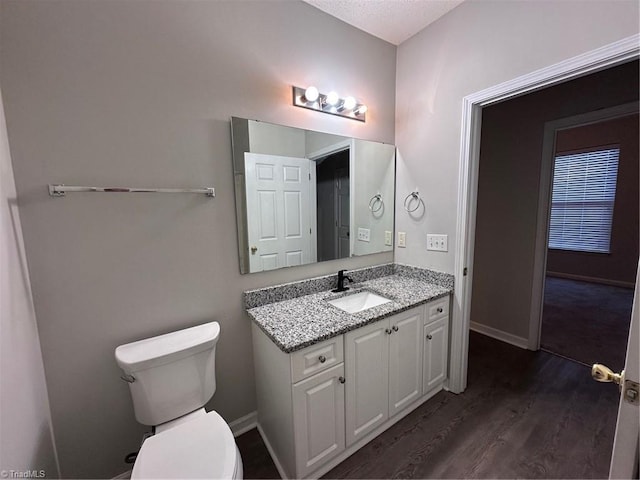 bathroom with wood-type flooring, toilet, vanity, and a textured ceiling