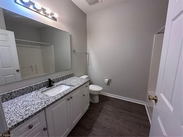 full bathroom featuring wood-type flooring, bathtub / shower combination, vanity, toilet, and a textured ceiling