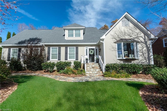 view of front facade with roof with shingles and a front yard