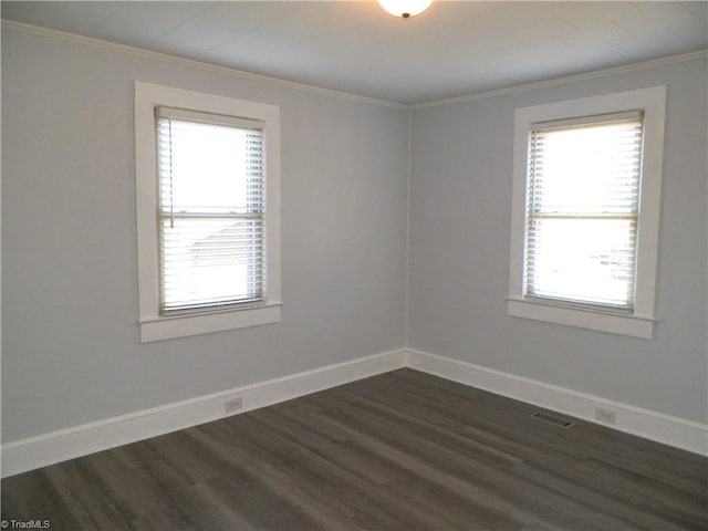 empty room featuring a healthy amount of sunlight, crown molding, and baseboards