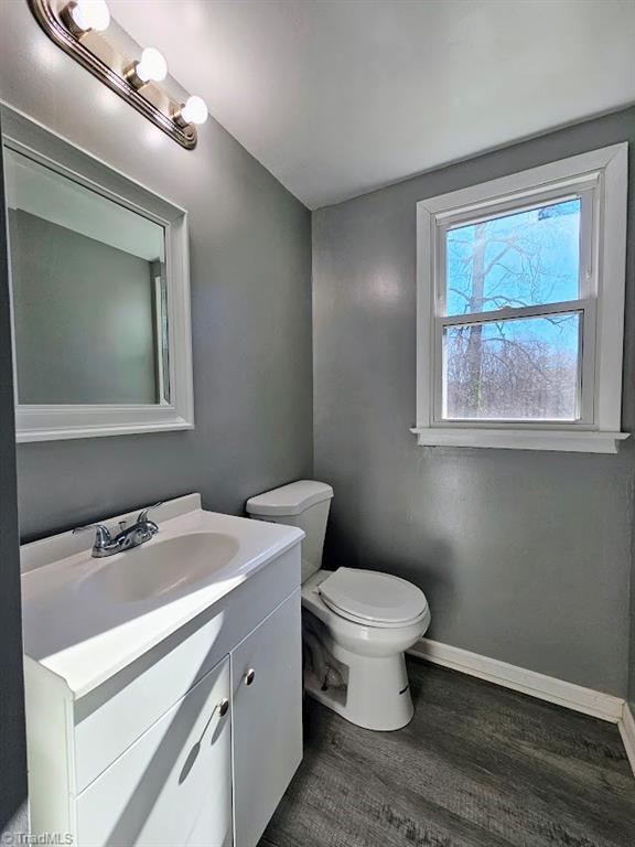 bathroom featuring wood-type flooring, vanity, and toilet