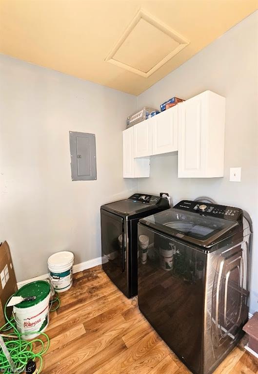 laundry room with cabinets, washing machine and clothes dryer, electric panel, and hardwood / wood-style flooring