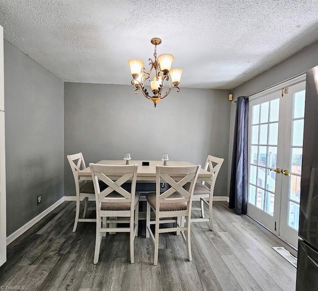 dining room featuring an inviting chandelier, hardwood / wood-style floors, a textured ceiling, and french doors