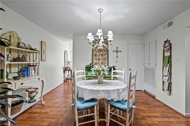 dining area featuring a textured ceiling, dark hardwood / wood-style floors, and an inviting chandelier