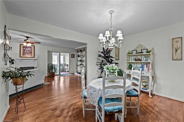 dining room with a textured ceiling, hardwood / wood-style floors, and ceiling fan with notable chandelier