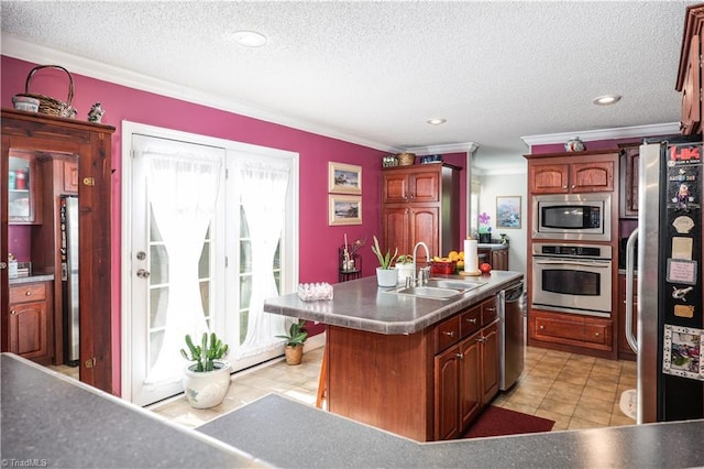 kitchen with a textured ceiling, crown molding, appliances with stainless steel finishes, a center island with sink, and a sink