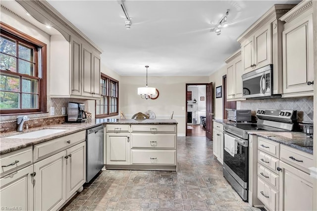 kitchen with rail lighting, sink, hanging light fixtures, tasteful backsplash, and stainless steel appliances