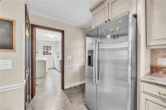 kitchen with backsplash, crown molding, light stone counters, and stainless steel refrigerator with ice dispenser