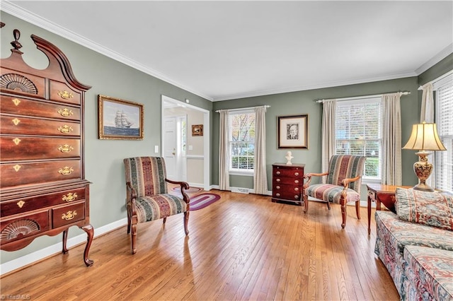 sitting room with crown molding and light hardwood / wood-style flooring