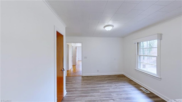 spare room with hardwood / wood-style floors and crown molding