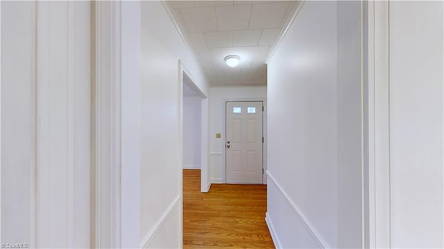 corridor with ornamental molding and light wood-type flooring