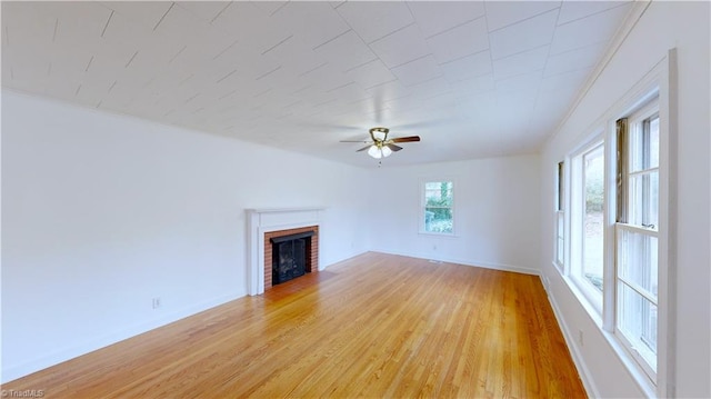 unfurnished living room with ceiling fan, light hardwood / wood-style floors, and a fireplace