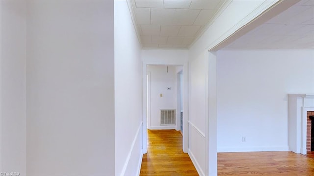 hallway with light hardwood / wood-style flooring and crown molding