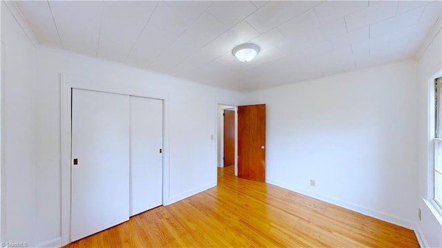 unfurnished bedroom featuring a closet, light hardwood / wood-style flooring, and crown molding