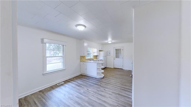 kitchen with sink, white refrigerator, white cabinets, and light hardwood / wood-style floors