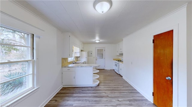 kitchen featuring white appliances, white cabinetry, sink, kitchen peninsula, and light hardwood / wood-style flooring