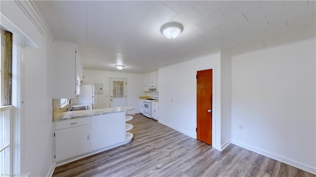 kitchen featuring white cabinets, white appliances, light hardwood / wood-style flooring, and sink