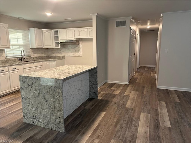 kitchen featuring dark hardwood / wood-style flooring, light stone counters, ornamental molding, sink, and white cabinets