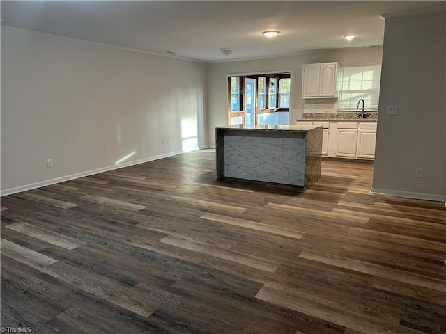 kitchen with a center island, sink, dark wood-type flooring, white cabinets, and ornamental molding