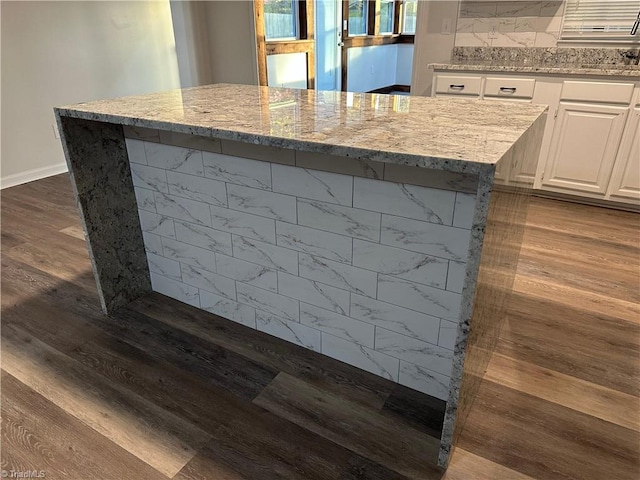 details featuring light stone counters, white cabinets, wood-type flooring, and a kitchen island