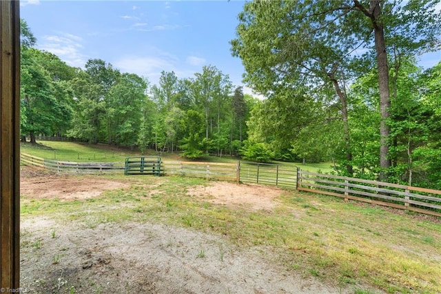 view of yard with a rural view, fence, and a wooded view