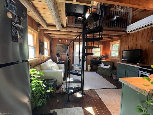 living room with wood walls, dark wood finished floors, stairs, a wall unit AC, and beamed ceiling