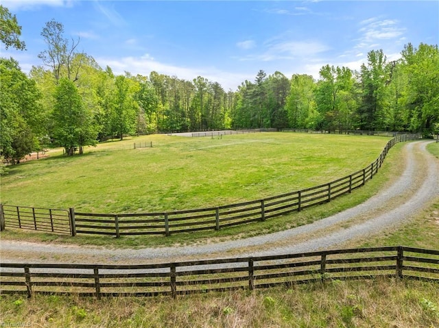 view of community with a lawn, fence, and a rural view