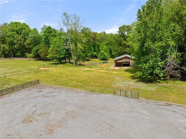 view of patio with fence, a detached carport, an outbuilding, and a rural view
