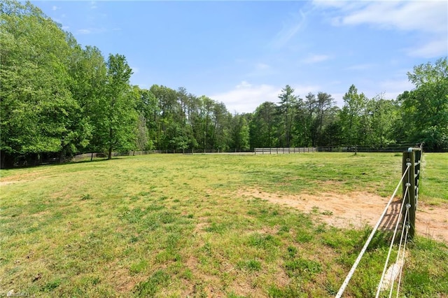 view of yard featuring fence, a rural view, and a forest view