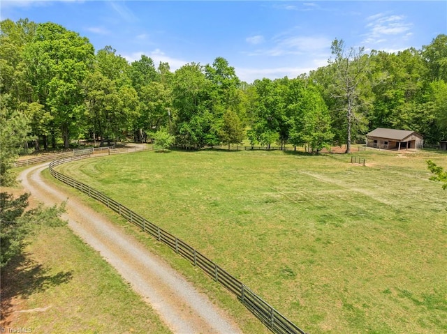 view of yard featuring fence, driveway, and a rural view