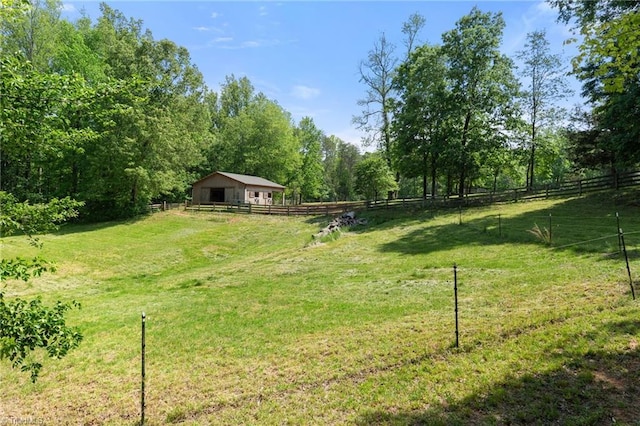 view of yard featuring fence, an outbuilding, and a rural view