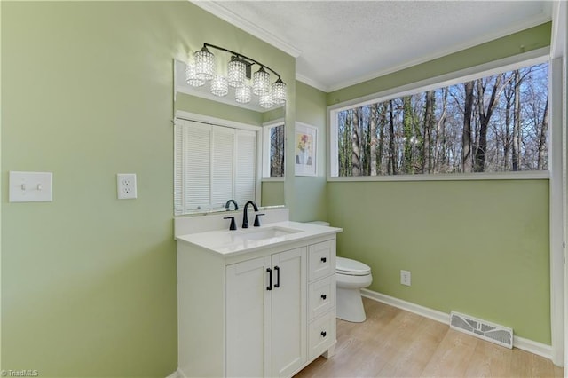 bathroom with baseboards, visible vents, toilet, wood finished floors, and vanity