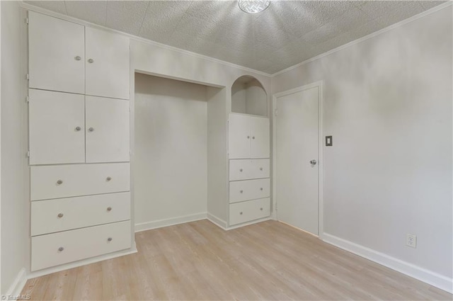 unfurnished bedroom with light wood-type flooring, a closet, a textured ceiling, and baseboards