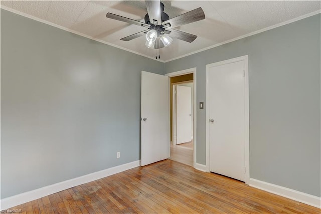 unfurnished room featuring baseboards, crown molding, hardwood / wood-style floors, and ceiling fan