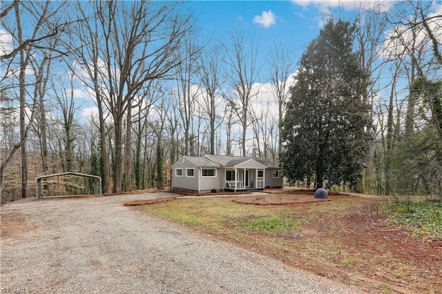 ranch-style house with a detached carport, covered porch, and driveway