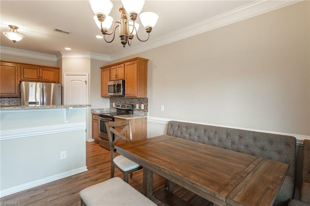 dining room featuring a notable chandelier, crown molding, and hardwood / wood-style flooring