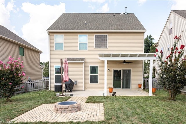 rear view of property featuring a fire pit, ceiling fan, a lawn, and a patio area