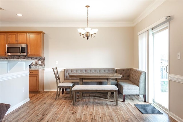 dining space with an inviting chandelier, ornamental molding, and light hardwood / wood-style floors