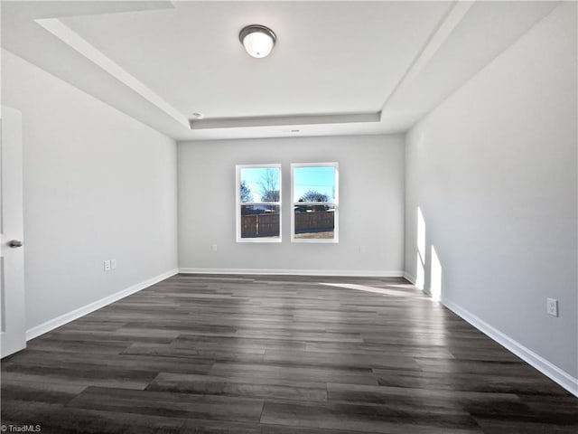 empty room with dark hardwood / wood-style floors and a raised ceiling