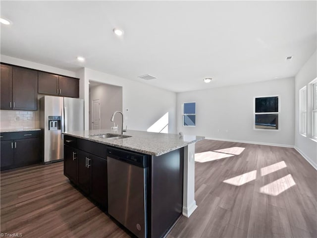 kitchen featuring sink, dark brown cabinets, appliances with stainless steel finishes, a kitchen island with sink, and backsplash