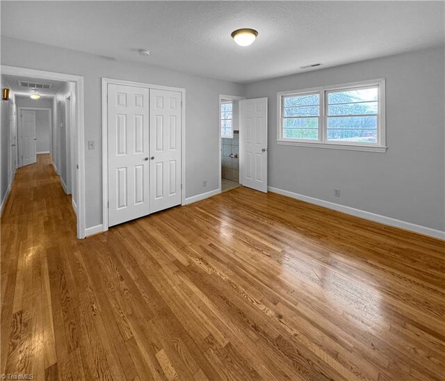 unfurnished bedroom featuring a closet, a textured ceiling, and hardwood / wood-style flooring