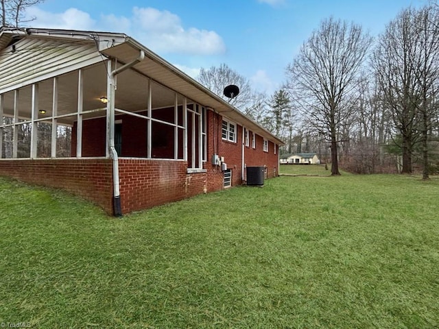 view of home's exterior featuring a sunroom, central air condition unit, and a lawn