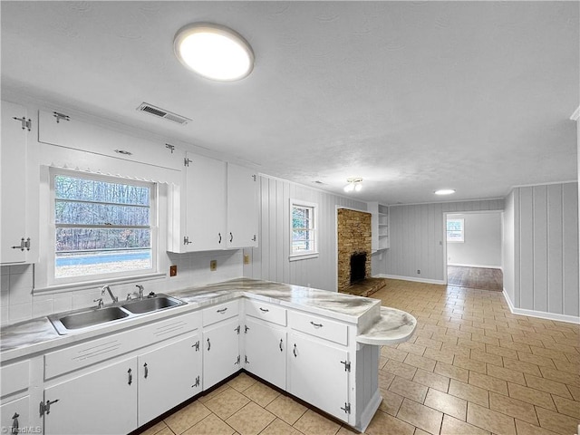 kitchen featuring kitchen peninsula, sink, white cabinets, and a fireplace