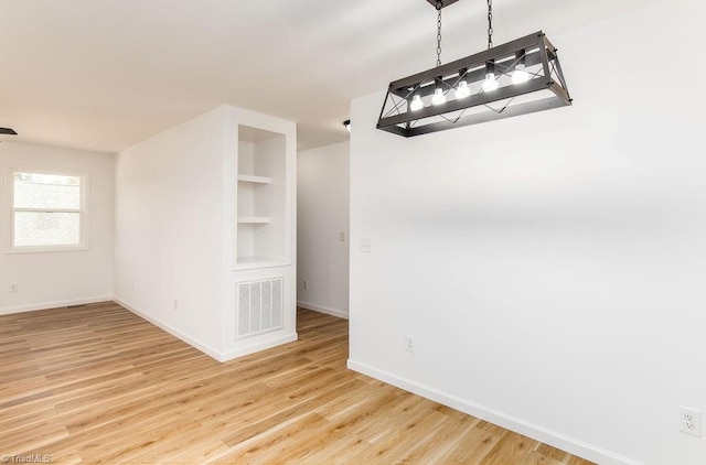 unfurnished dining area with built in shelves and wood-type flooring